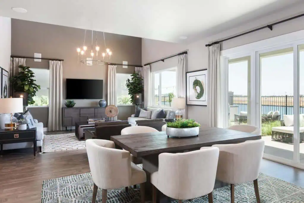 Haven and Reflections Architecture Blog 1 River Islands Open concept living and dining area with a dark wood dining table beige chairs and a chandelier in a sunlit home