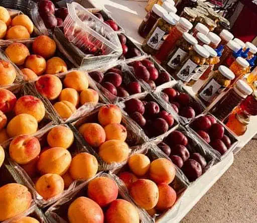 2019photo5 River Islands Rows of peaches apricots and plums arranged in baskets at a market stall with jars of honey in the background