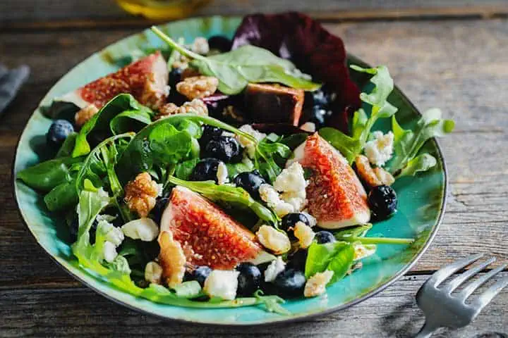 RIBlogInSeasonRecipes20230911FigSalad720 River Islands fig and arugala salad in blue bowl
