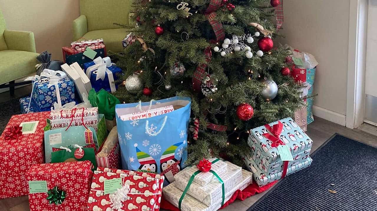 Christmas tree with red and silver ornaments surrounded by many wrapped gifts with bows on the floor under it