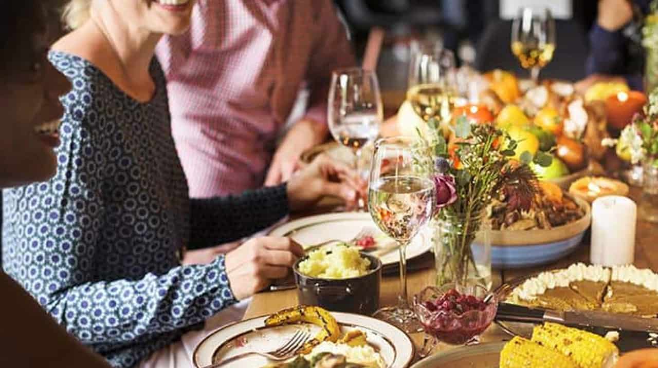 People dining at a festive table with wine glasses flowers and a spread of dishes