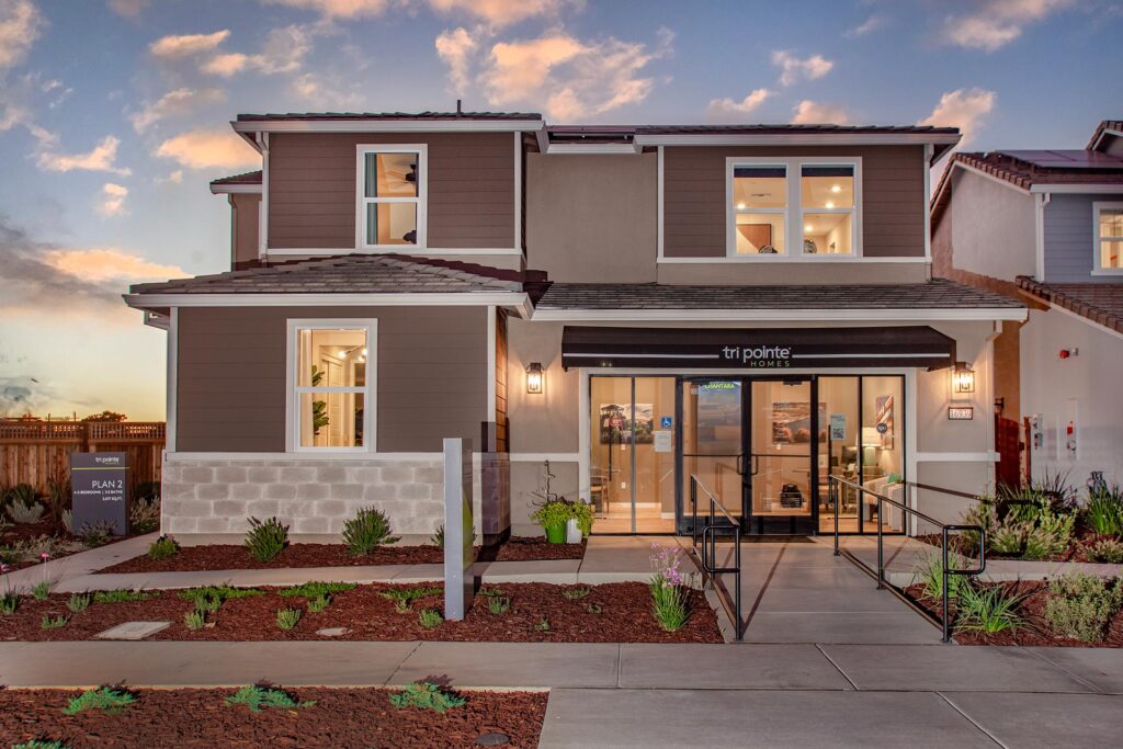 Two story model home with a black awning reading Tri Pointe Homes glass entry doors and a wheelchair ramp