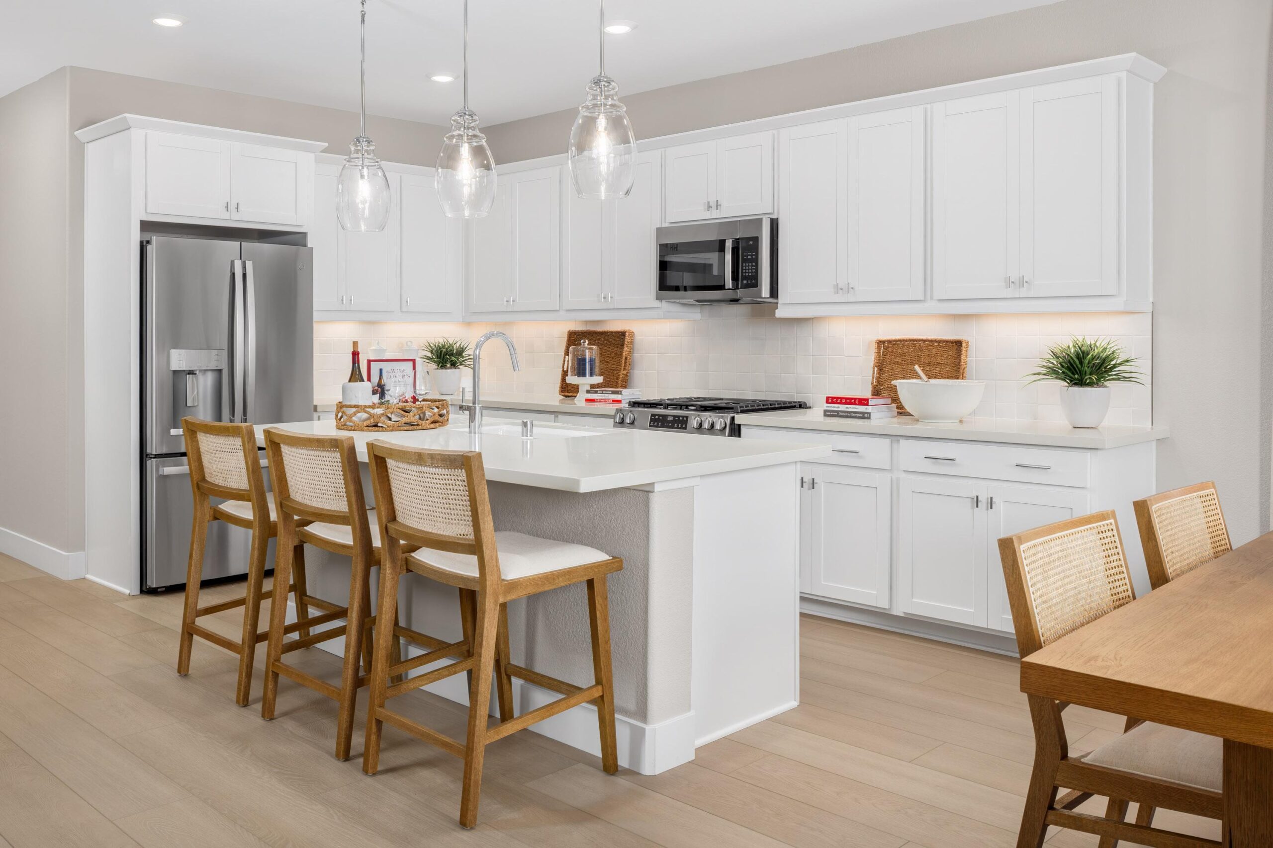 Modern kitchen in Bridgeway Plan 3501 at River Islands featuring white cabinetry, stainless steel appliances, and a central island with seating.