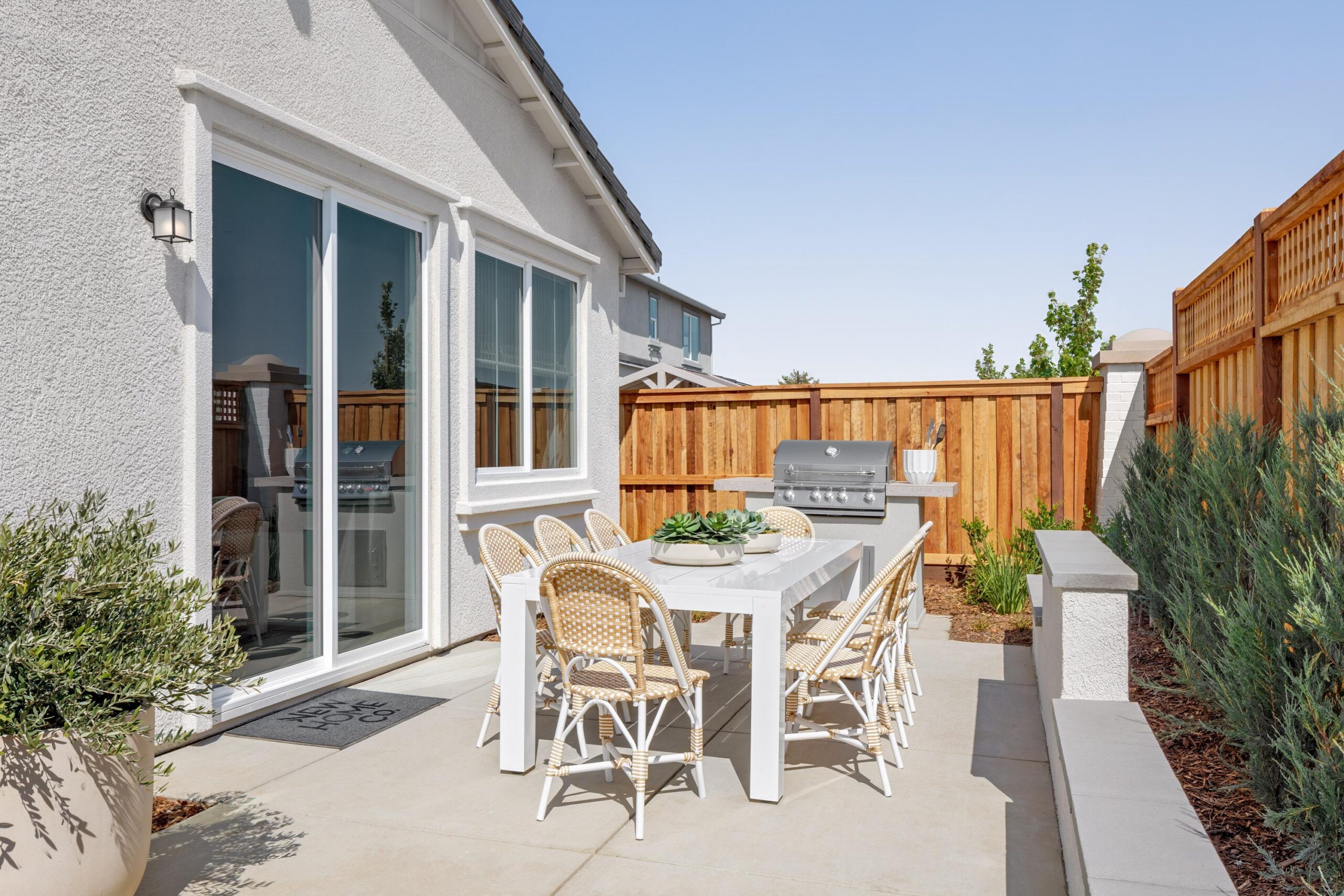 Outdoor patio of Bridgeway Plan 3501 at River Islands with dining set, BBQ grill, and privacy fencing for relaxed entertaining and family gatherings.