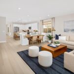 Open-concept living room in Bridgeway Plan 3501 at River Islands with modern furnishings, large windows, and seamless flow into the kitchen.