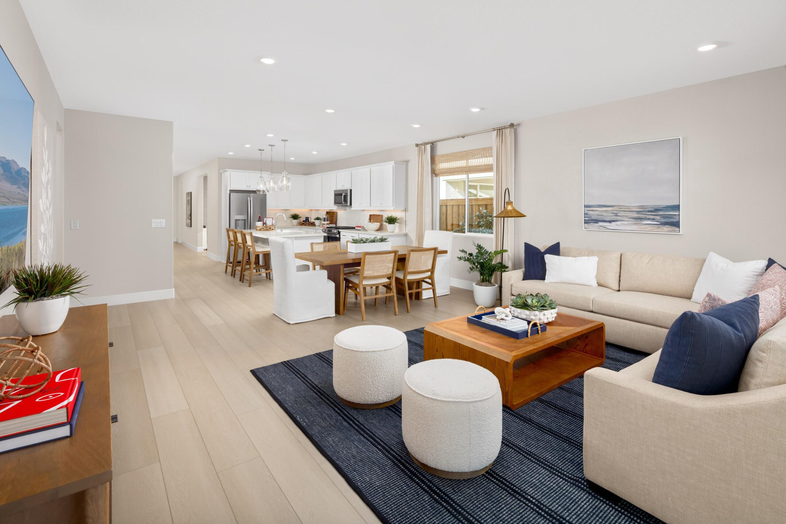 Open-concept living room in Bridgeway Plan 3501 at River Islands with modern furnishings, large windows, and seamless flow into the kitchen.