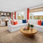 Open-concept living room and kitchen in Bridgeway Plan 3502 with bright natural light, white sectional sofa, and modern wood cabinetry.