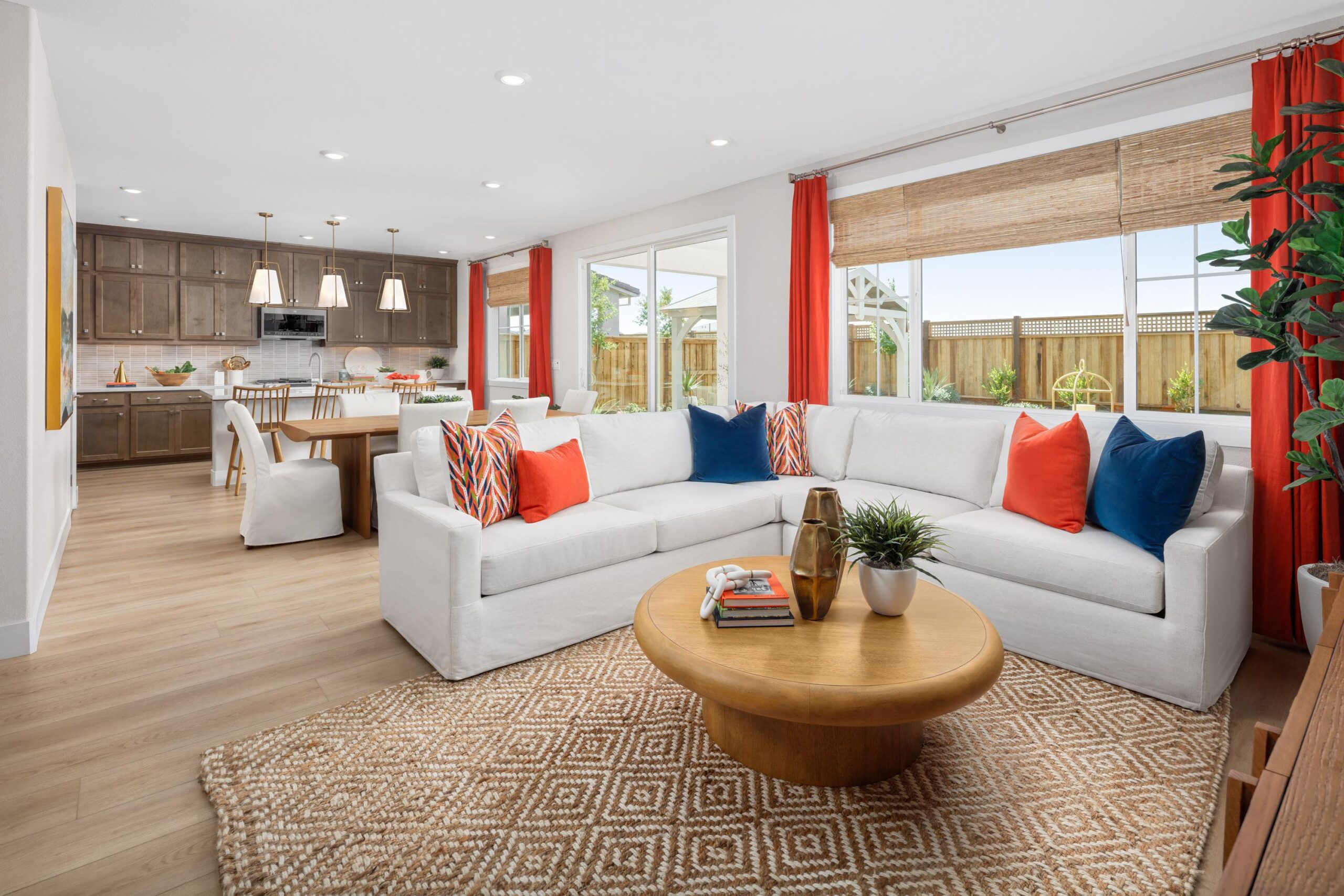 Open-concept living room and kitchen in Bridgeway Plan 3502 with bright natural light, white sectional sofa, and modern wood cabinetry.