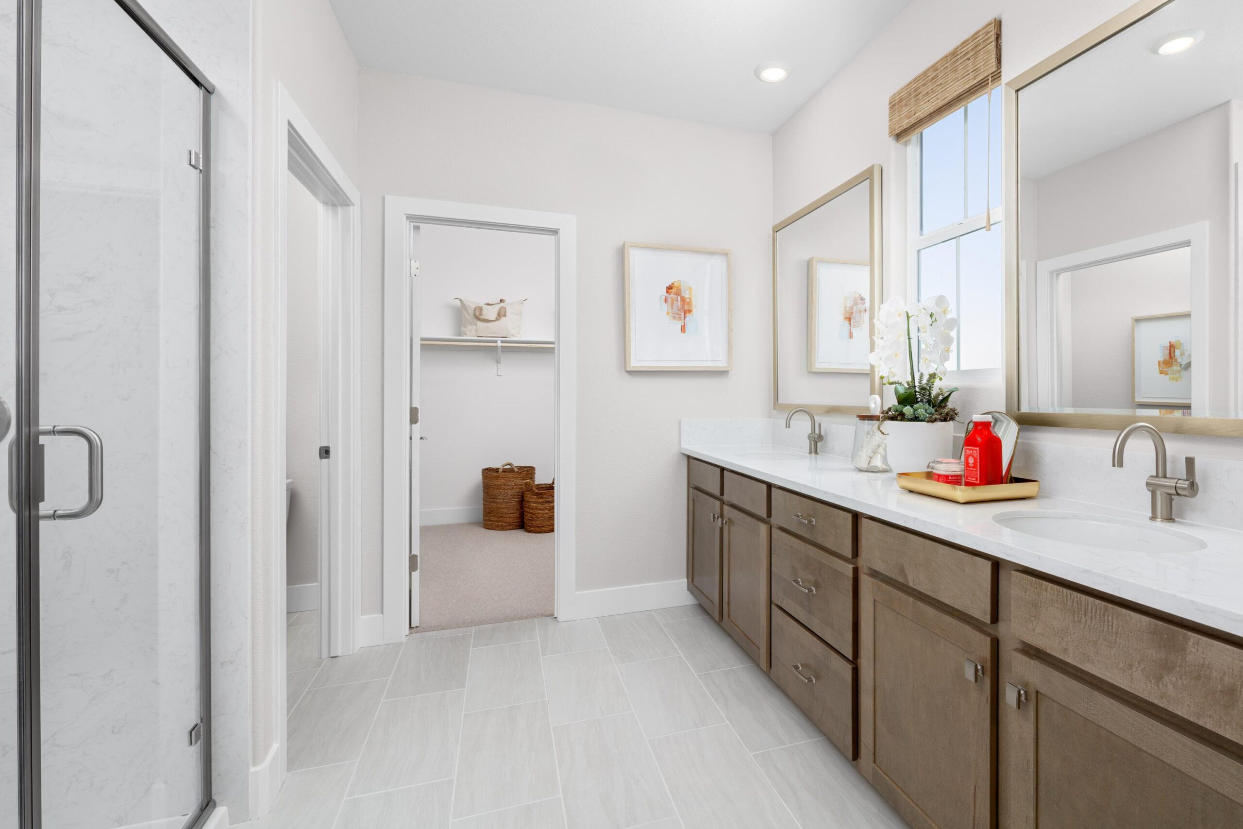 Elegant primary bathroom in Bridgeway Plan 3502 with dual-sink vanity, framed mirrors, and walk-in closet access.