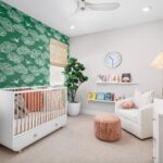 Charming nursery in Bridgeway Plan 3502 with accent wallpaper, white crib, and cozy reading corner.