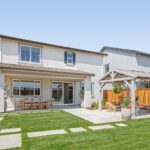 Bridgeway Plan 3502 backyard with covered patio, outdoor dining space, and landscaped lawn.