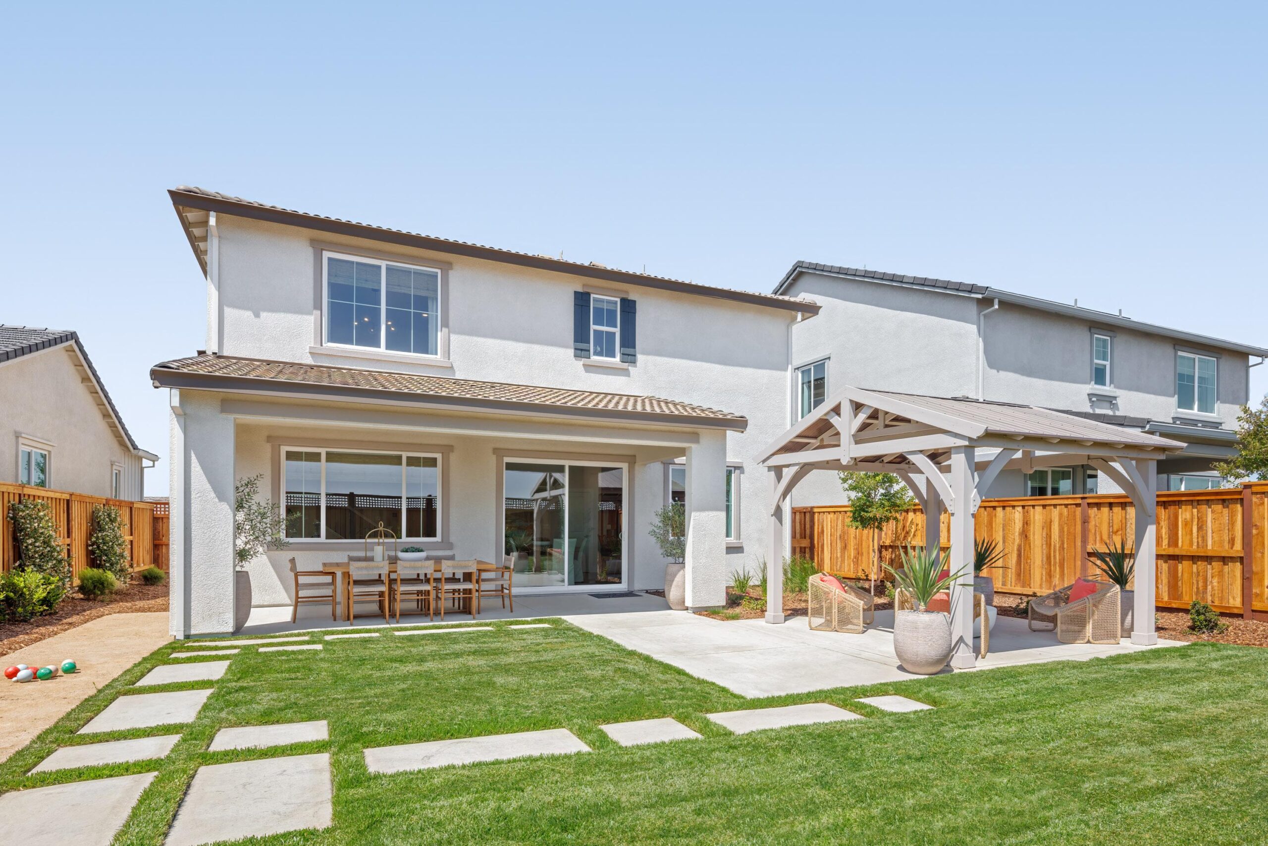 Bridgeway Plan 3502 backyard with covered patio, outdoor dining space, and landscaped lawn.