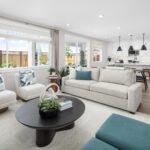 Open-concept living room and kitchen in Bridgeway Plan 3503 at River Islands featuring modern white cabinetry, black pendant lighting, and spacious seating.
