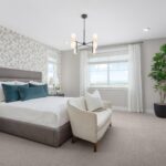 Elegant primary bedroom in Bridgeway Plan 3503 with feature wallpaper accent wall, teal decor accents, and large windows with natural light.