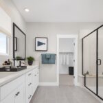 Luxurious primary bathroom in Bridgeway Plan 3503 at River Islands with dual vanities, walk-in shower, and direct access to a spacious closet.