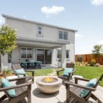 Outdoor living space at Bridgeway Plan 3503 featuring a landscaped backyard with fire pit, seating area, and covered dining patio.