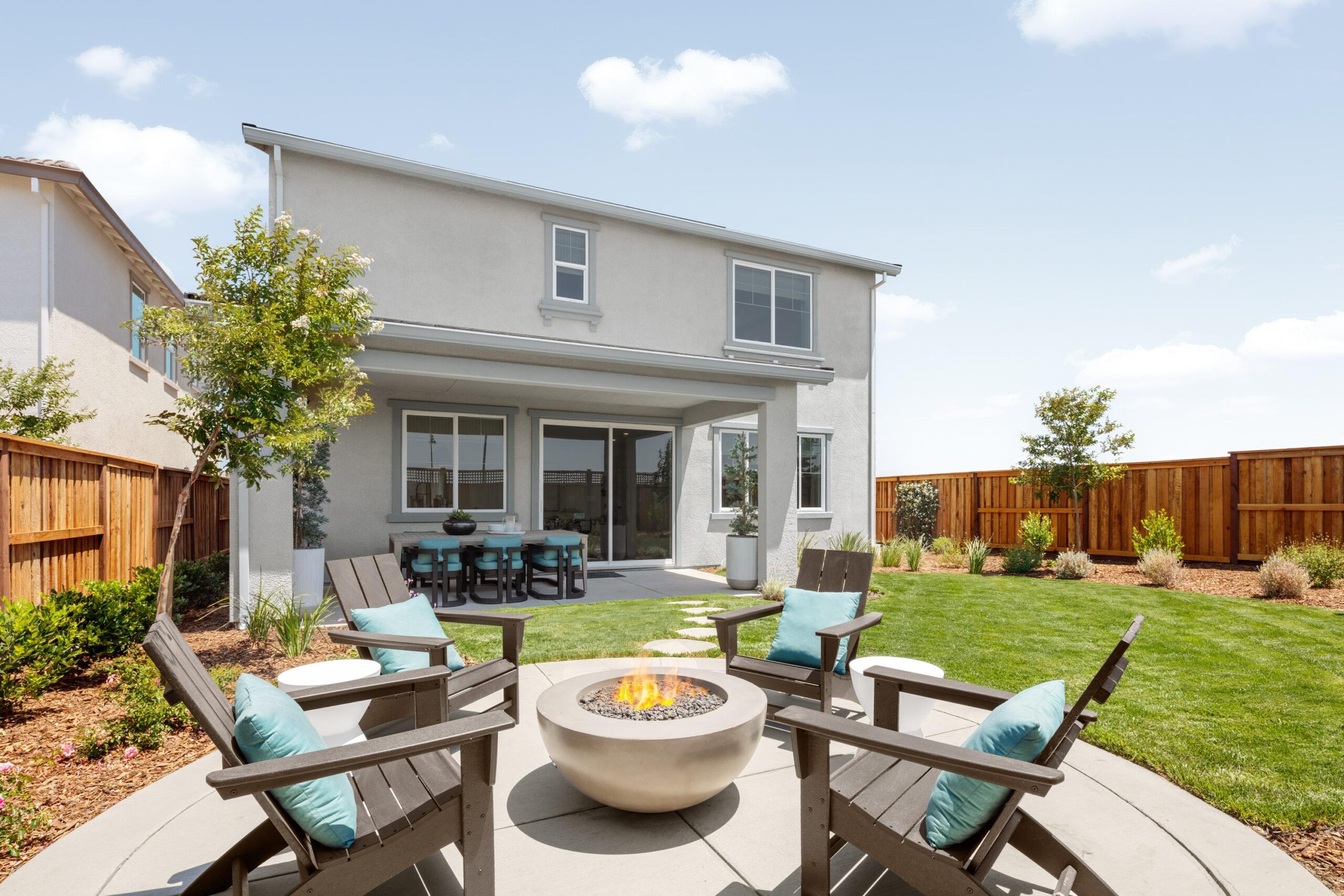 Outdoor living space at Bridgeway Plan 3503 featuring a landscaped backyard with fire pit, seating area, and covered dining patio.
