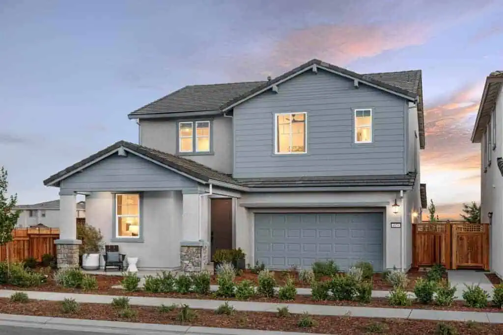 Two story exterior of Bridgeway Plan 3503 by New Home Company at River Islands with blue siding accents two car garage and landscaped front yard