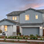 Two-story exterior of Bridgeway Plan 3503 by New Home Company at River Islands with blue siding accents, two-car garage, and landscaped front yard.