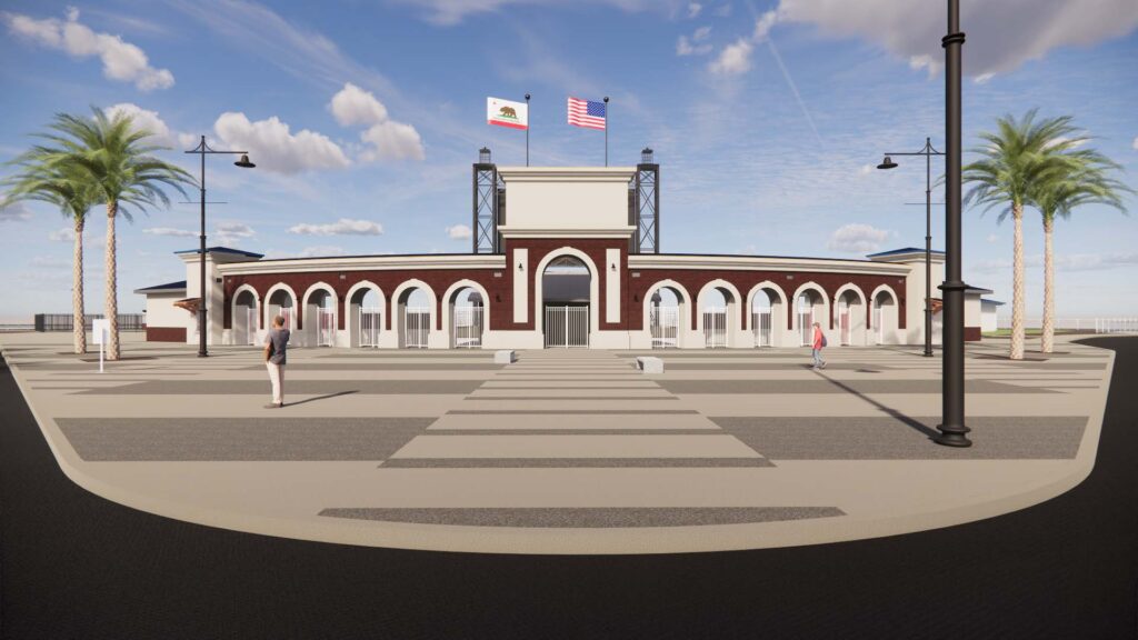 Brick building with arched entries and central archway on a plaza, flanked by California and US flags in clear blue sky.